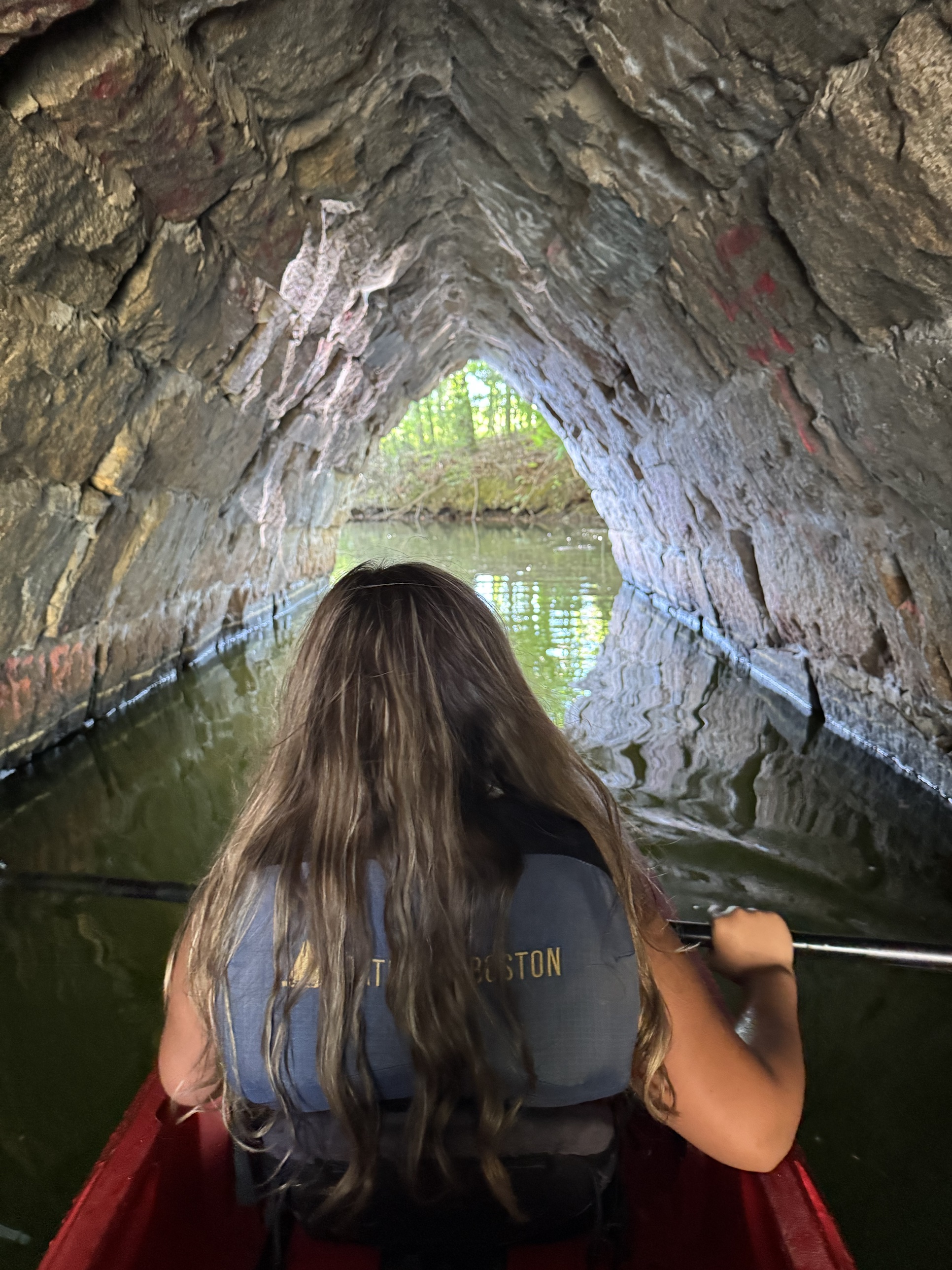 Jenn's youngest kayaking through a stone tunnel toward the light at a state park